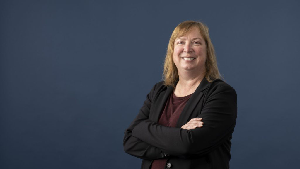 Shelley Minteer, with shoulder-length blonde hair, wearing a suit and red shirt