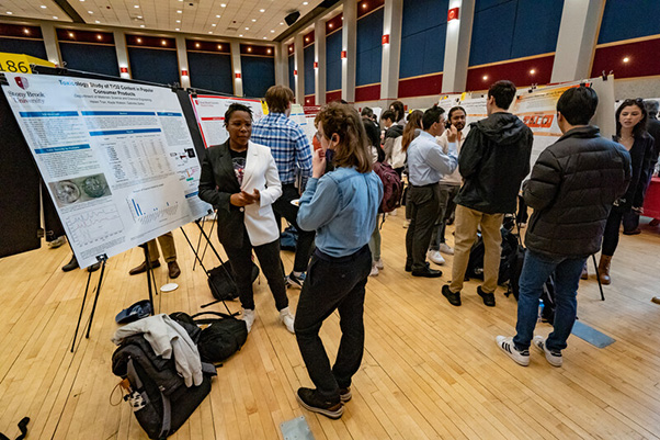 Undergraduate Research and Creative Activities (URECA) A crowded scientific conference hall with diverse attendees discussing research posters. The atmosphere is energetic, collaborative, and focused.
